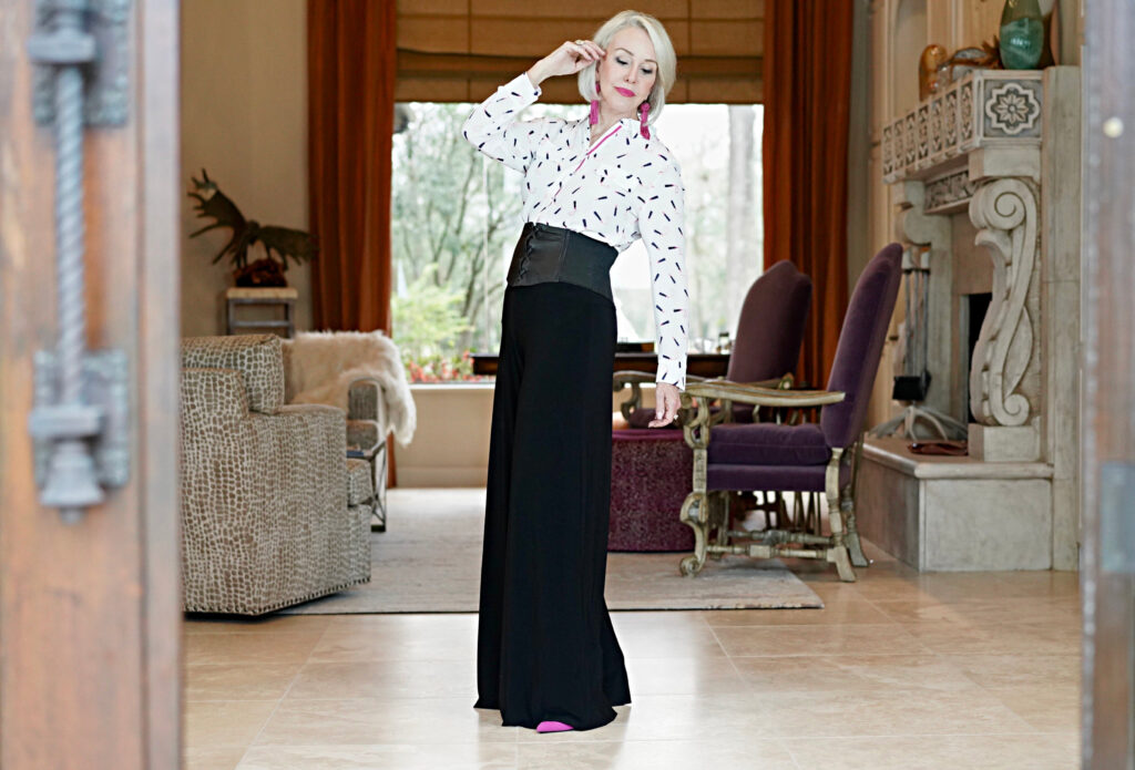 Sheree Frede of the SheShe Show standing in foyer wearing black pants and white print shirt