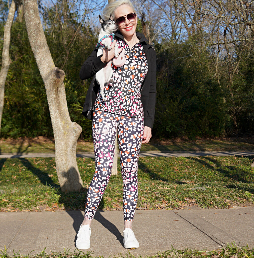 Sheree Frede of the SheShe Show walking toy fox terrrier wearing print leggings and zip knit jacket zenergy