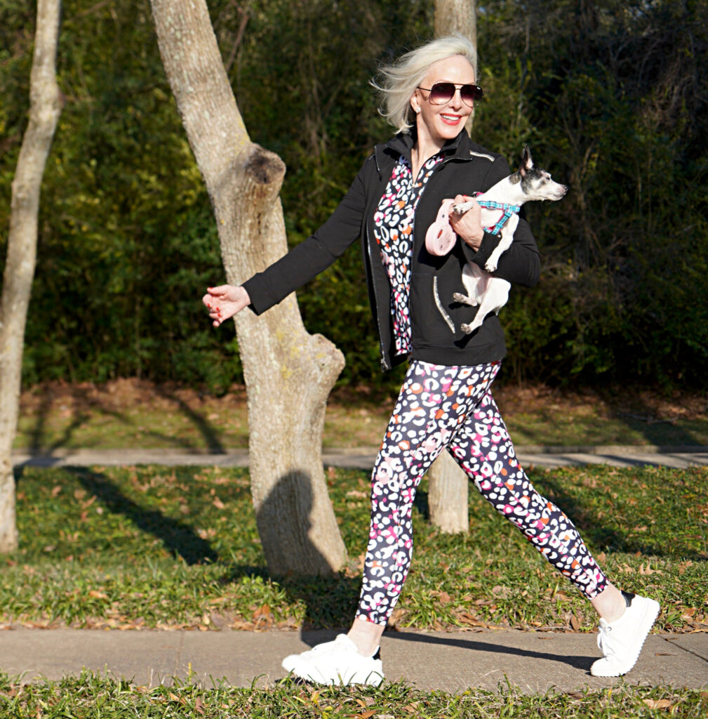 Sheree Frede of the SheShe Show walking toy fox terrrier wearing print leggings and zip knit jacket zenergy