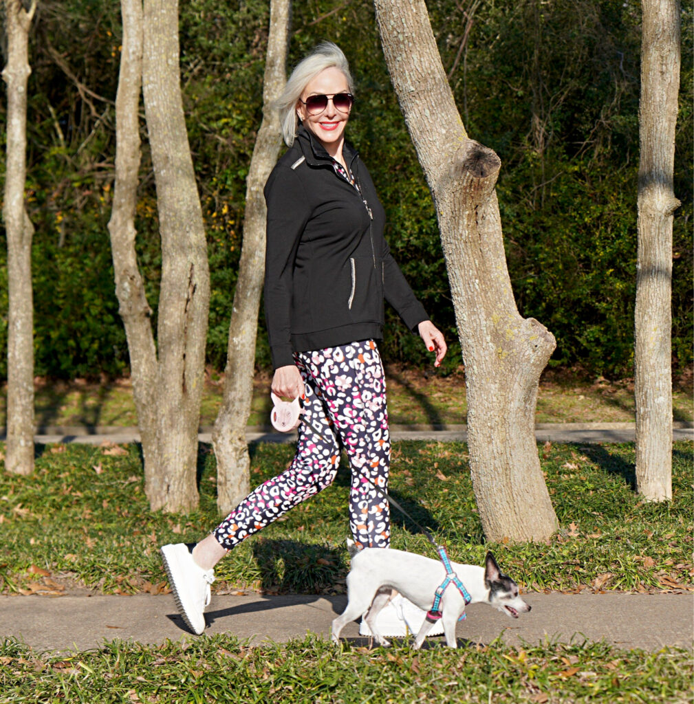 Sheree Frede of the SheShe Show walking toy fox terrrier wearing print leggings and zip knit jacket zenergy