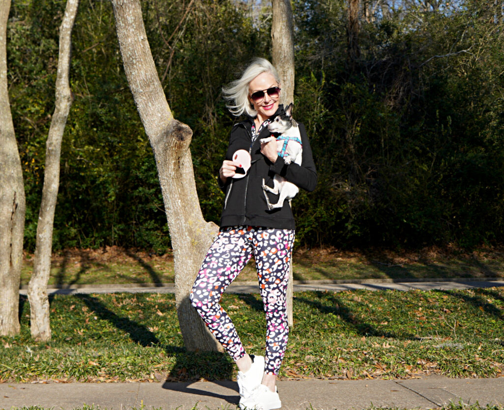 Sheree Frede of the SheShe Show walking toy fox terrrier wearing print leggings and zip knit jacket zenergy