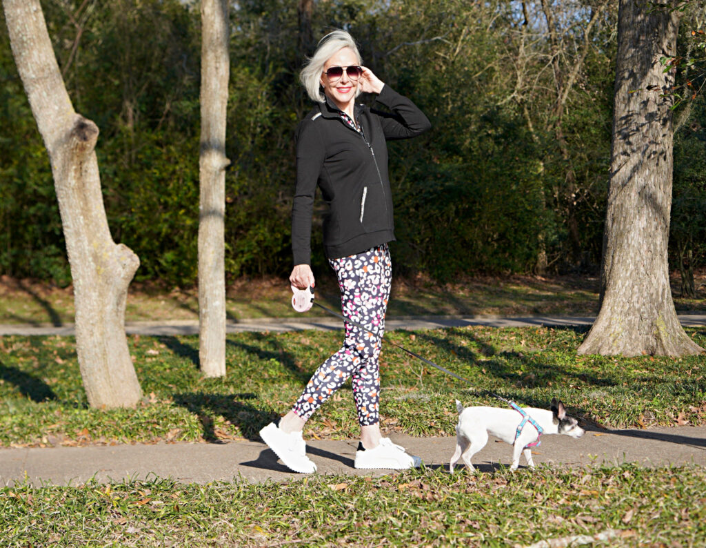 Sheree Frede of the SheShe Show walking toy fox terrrier wearing print leggings and zip knit jacket zenergy