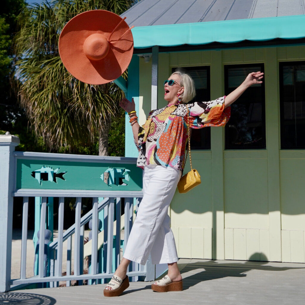 Sheree Frede of the SheShe Show wearing a multi color printed top and big orange hat