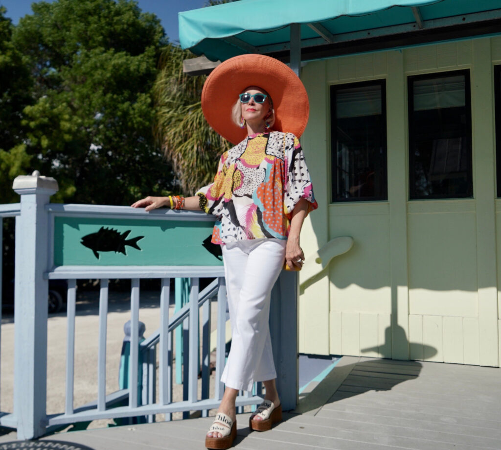 Sheree Frede of the SheShe Show wearing a multi color printed top and big orange hat