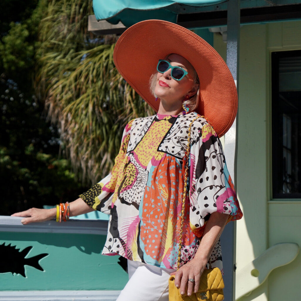 Sheree Frede of the SheShe Show wearing a multi color printed top and big orange hat