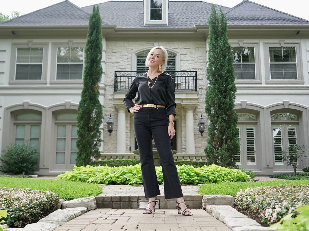 Sheree Frede of the SheShe Shoe standing n front of white house wearing all black jeans and top