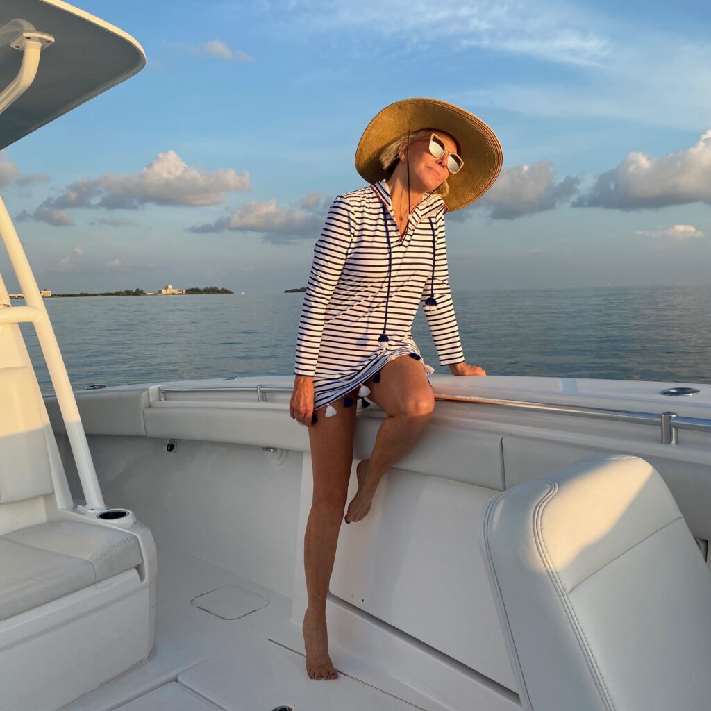 Sheree Frede of the SheShe Show sitting on boat wearing a navy and white strip dress
