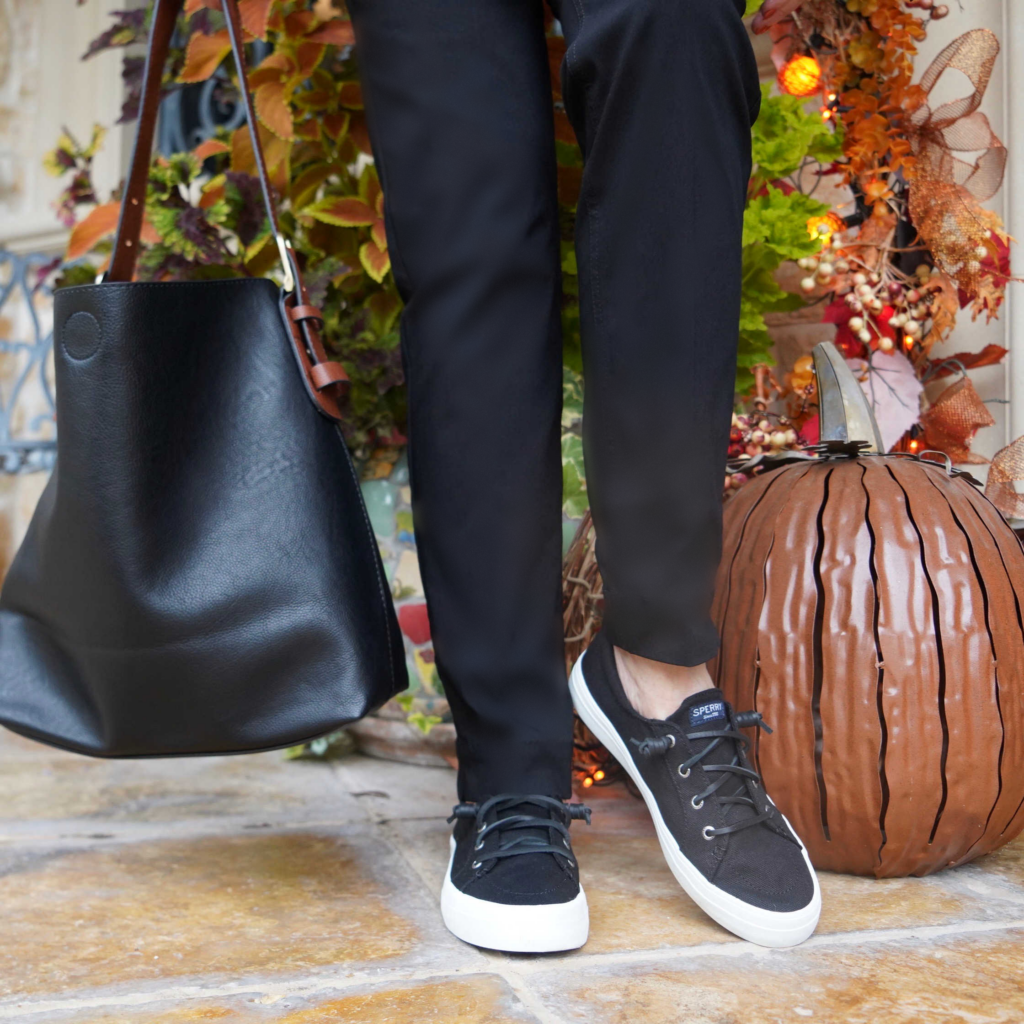 Sheree Frede of the SheShe Show holding black leather tote bag and wearing black Sperry sneakers