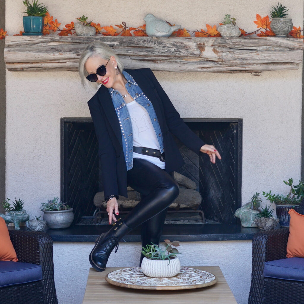 Sheree Frede of the SheShe Show standing in front of outdoor fireplace wearing black blazer and, faux leather jeggings and combat boots.