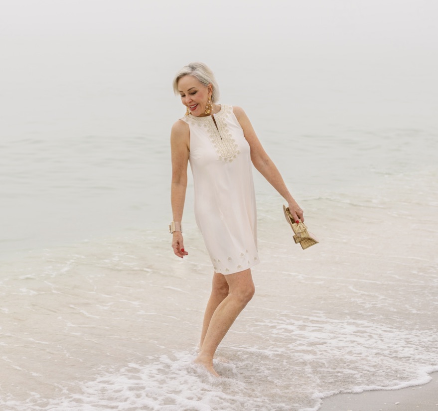 Sheree Frede of the SheShe SHow & shopping network walking in the waters edge wearing a white Cabana life dress