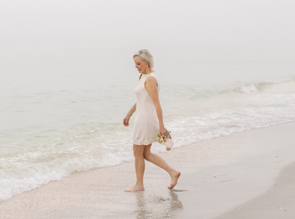 Sheree Frede of the SheShe SHow & shopping network walking in the waters edge wearing a white Cabana life dress