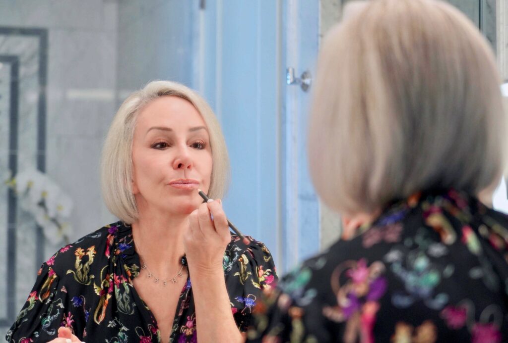 Sheree Frede putting on lip liner in mirror