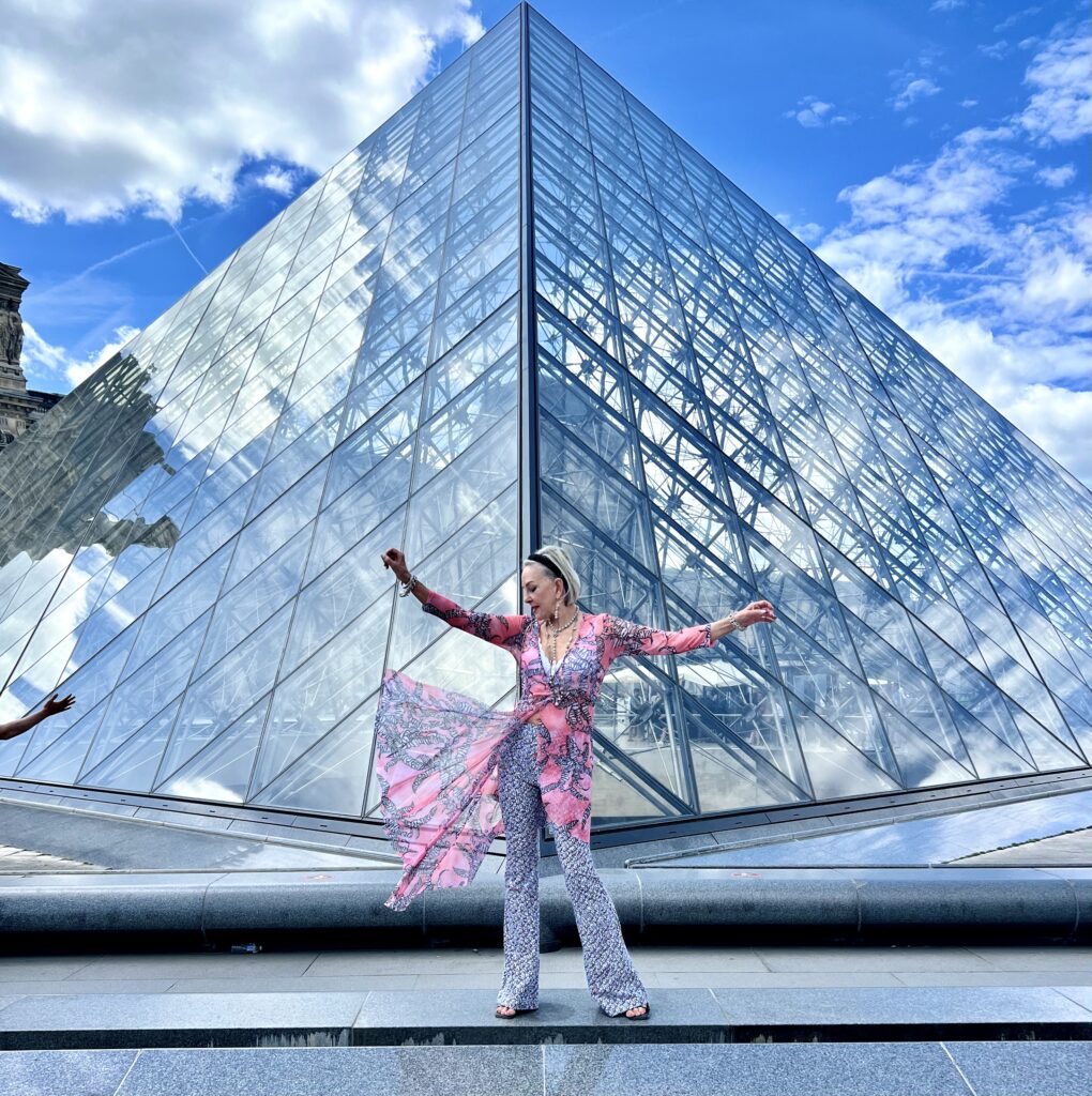 Sheree posing in front of the pyramid at the Louvre en Paris wearing a black, white and pink outfit by Ala Von Auersperg