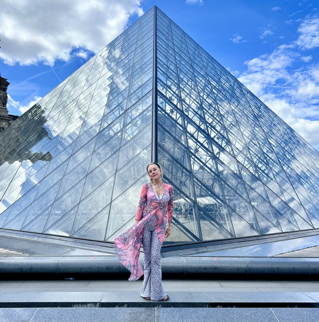 Sheree posing in front of the pyramid at the Louvre en Paris wearing a black, white and pink outfit by Ala Von Auersperg
