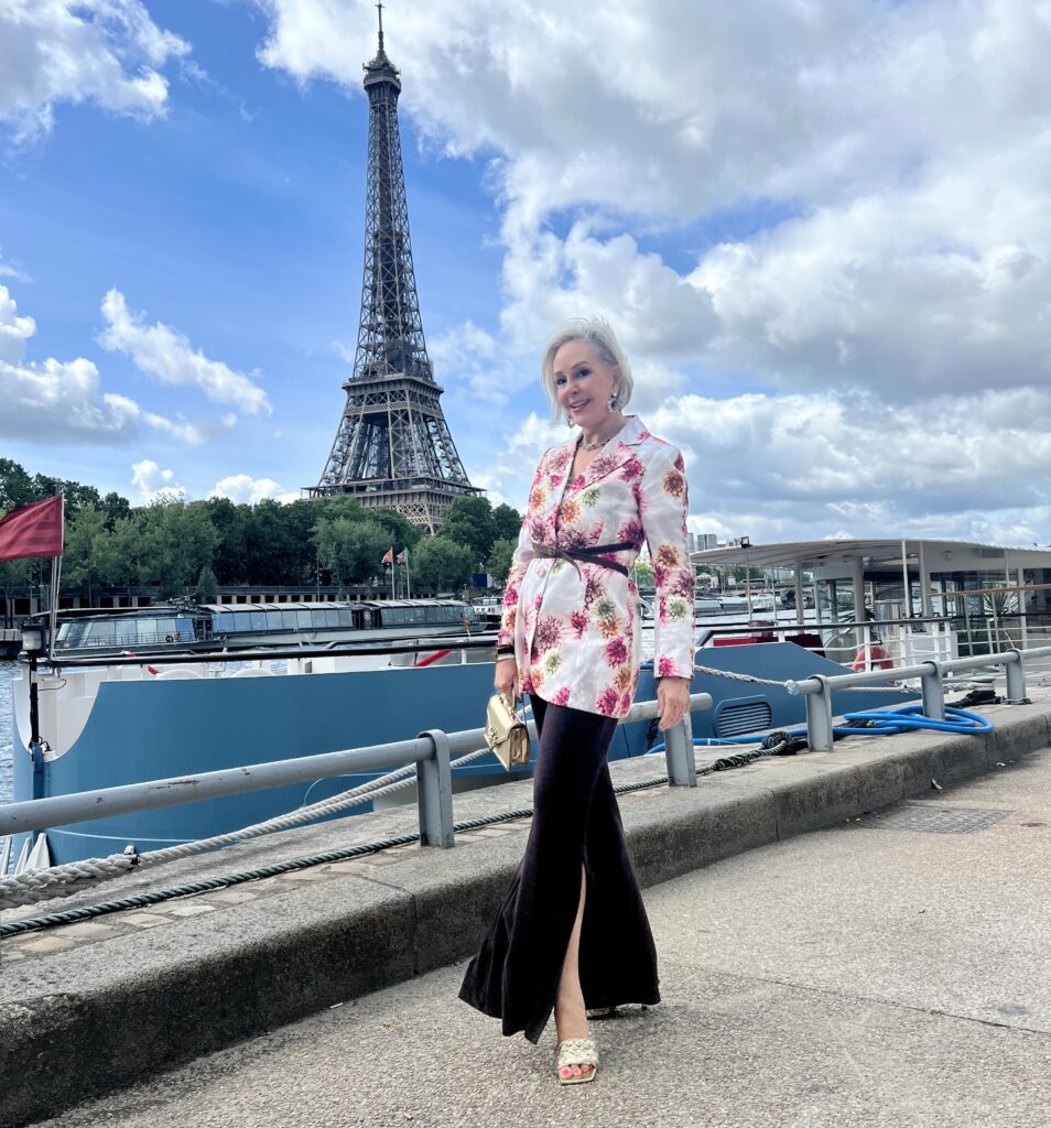 Sheree posing in front of the pyramid at the Louvre en Paris wearing a white floral blazer by Ala Von Auersperg