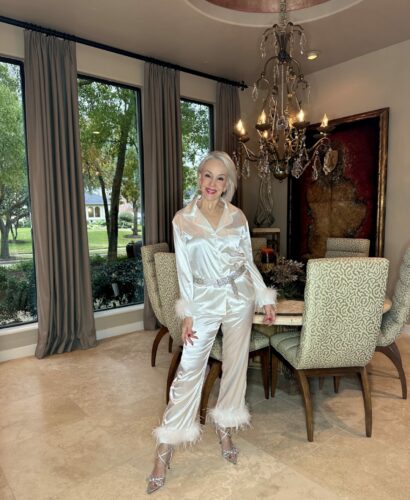 Sheree Frede of the SheShe Show wearing a white satin pajama set with feather trim sleeves to wear in New Year