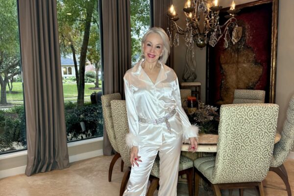 Sheree Frede of the SheShe Show wearing a white satin pajama set with feather trim sleeves to wear in New Year