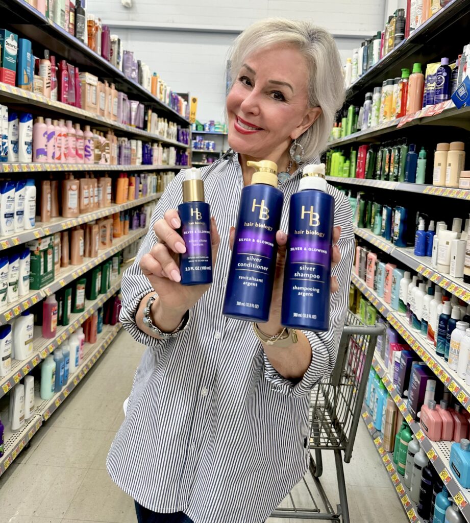 Sheree Frede of the SheShe Show standing in the aisle at Walmart holding 3 Hair Bilolgy products.