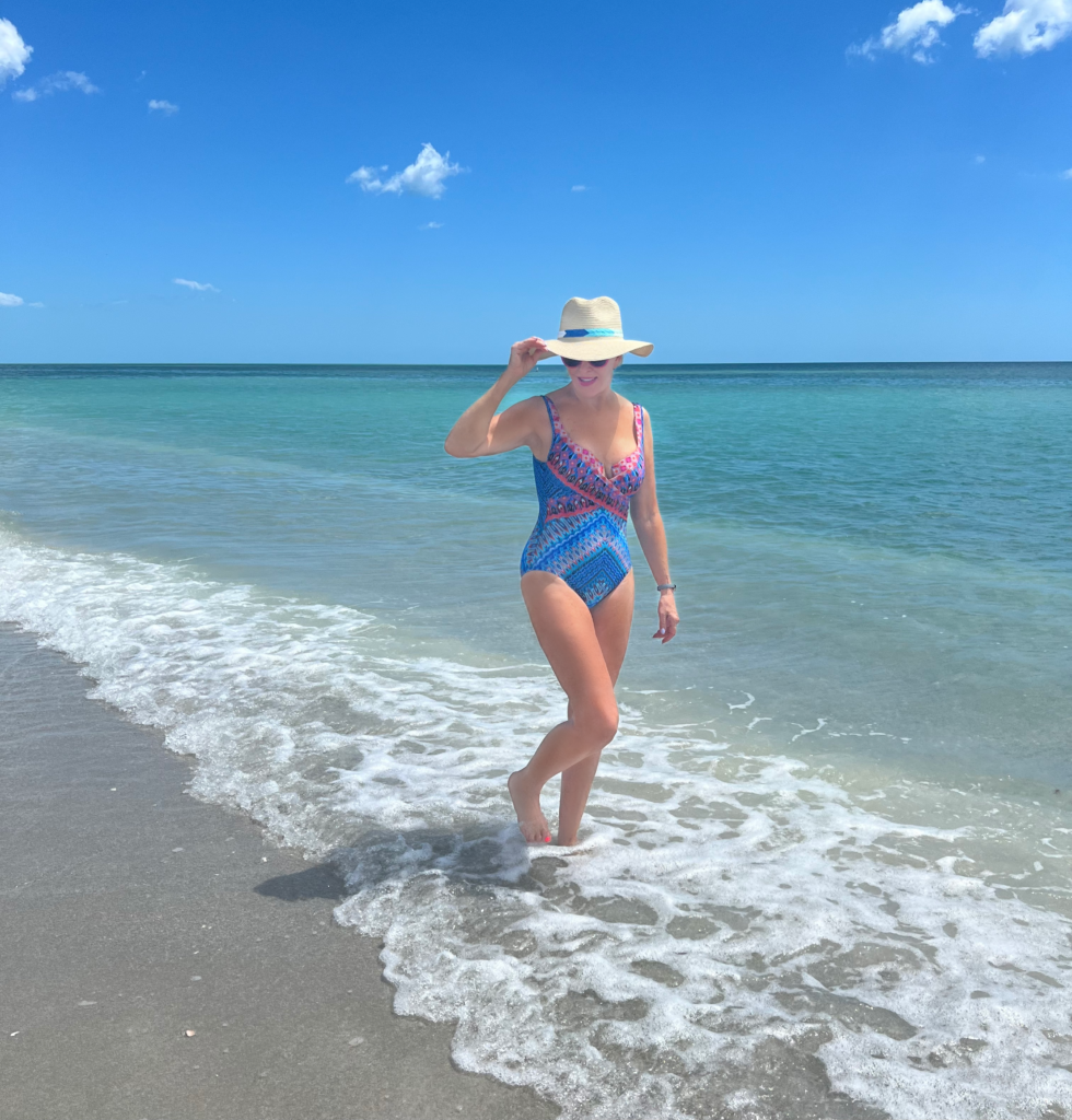 Sheree Frede walking by the beach in a Miraclesuit swimsuit