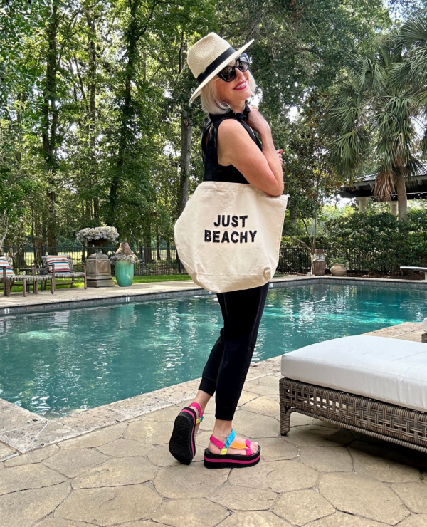 Sheree Frede wearing a casual black jumpsuit carrying her Just Beach Beach bag