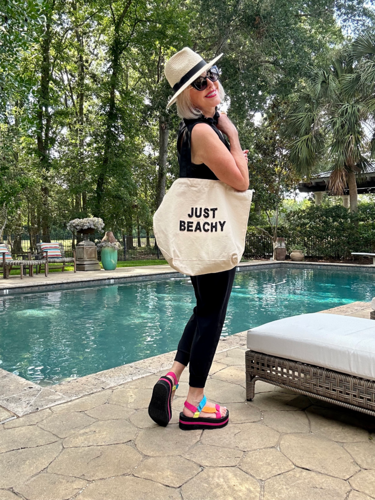 Sheree Frede wearing a casual black jumpsuit carrying her Just Beach Beach bag