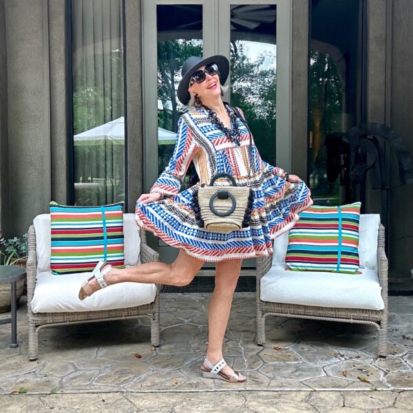 Sheree Frede of the SheSheShow wearing a Festive 4th of July style outfit in a red white and blue skater dress, black hat, rattan handbag and white sandals