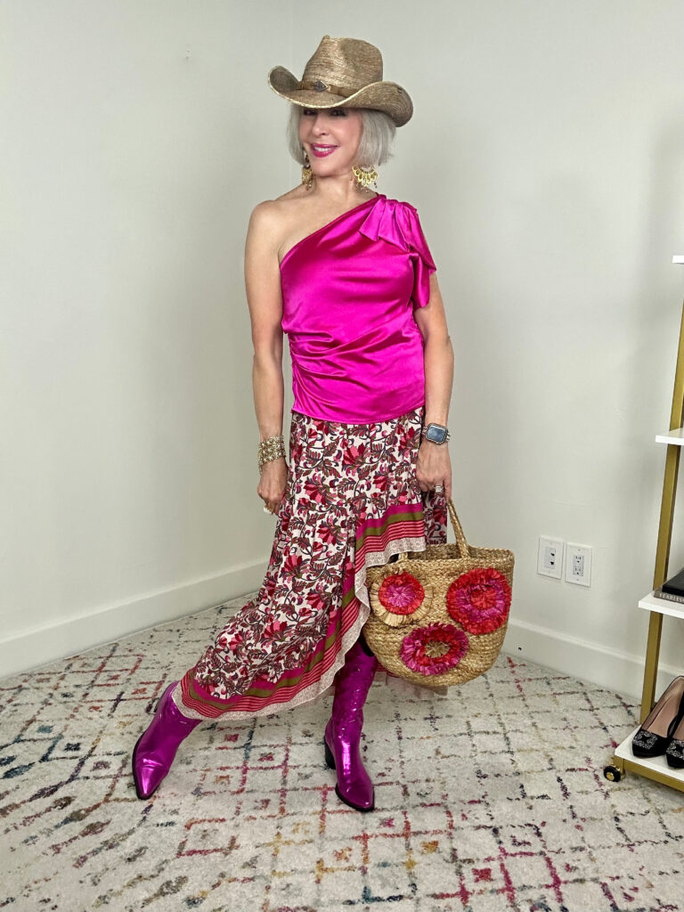 Sheree of the SheShe Show wearing a hot pink one shoulder satin top and floral high/low skirt with metallic pink cowboy boots with floral straw tote and raffia western hat