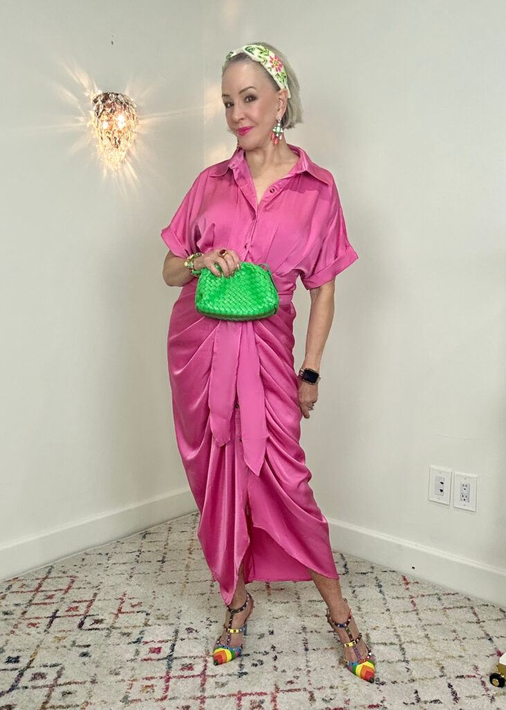 Sheree of the SheShe Show wearing a hot pink satin midi dress with lime green bag and multi colored heels