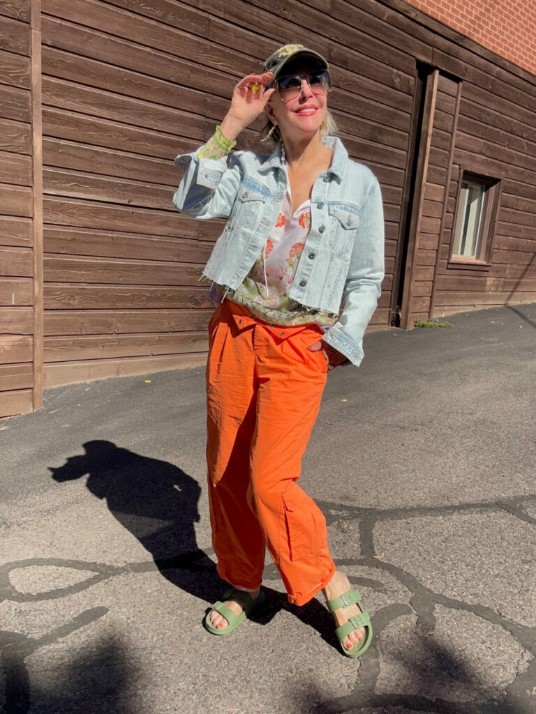 Sheree wearing orange cargo pants with a crop denim jacket and slide sandals