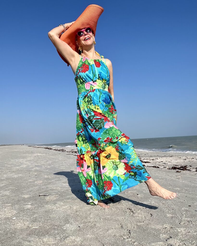 Sheree Frede of SheSheShow on beach in floral dress for resort wear