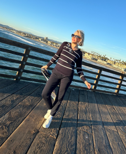 Sheree Frede @shesheshow on the Oceanside, Ca Pier wearing navy joggers and navy and white stripe sweater.