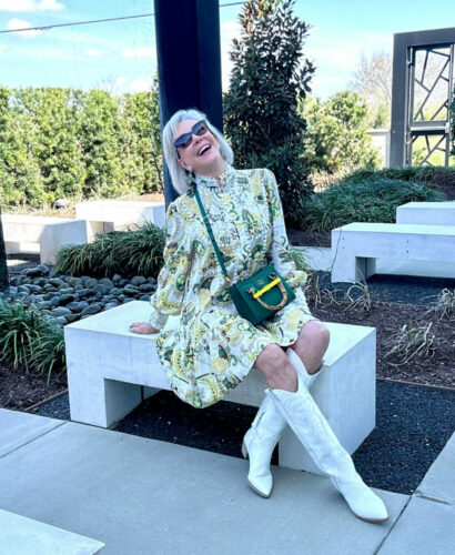Sheree Frede celebrating in a white and yellow print dress wearing white cowboy boots