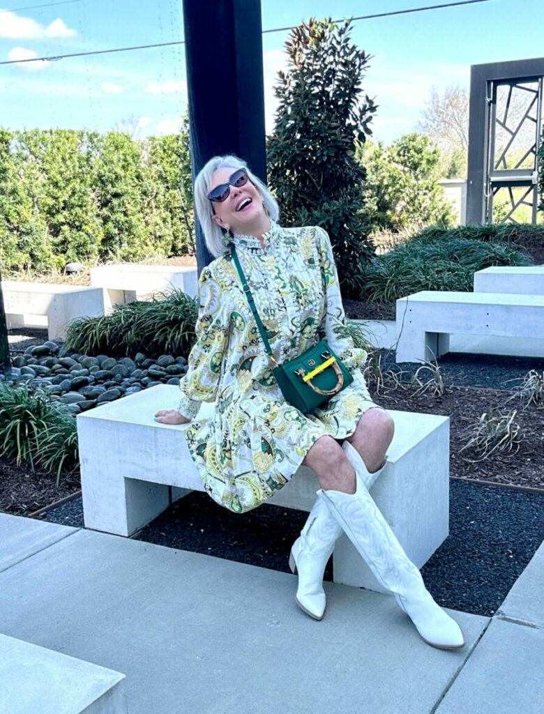 Sheree Frede sitting in a white and yellow print dress wearing white cowboy boots