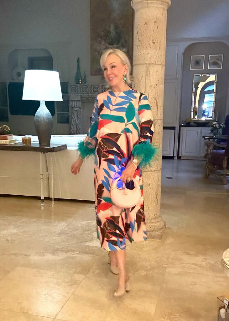 Sheree Frede Wearing a colorful palmprint maxi dress with green feather cuffs