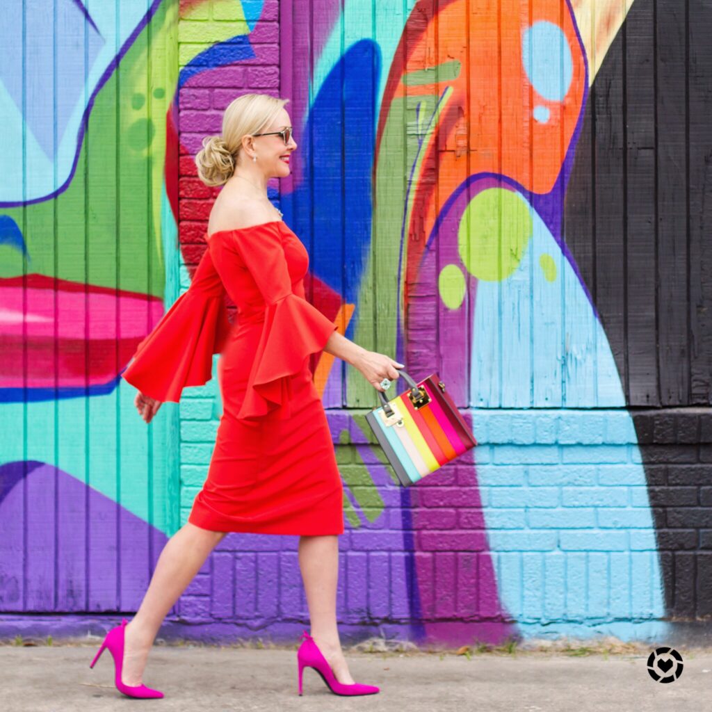 Sheree Frede wearing a bright red off the should dress in front of colorful mural