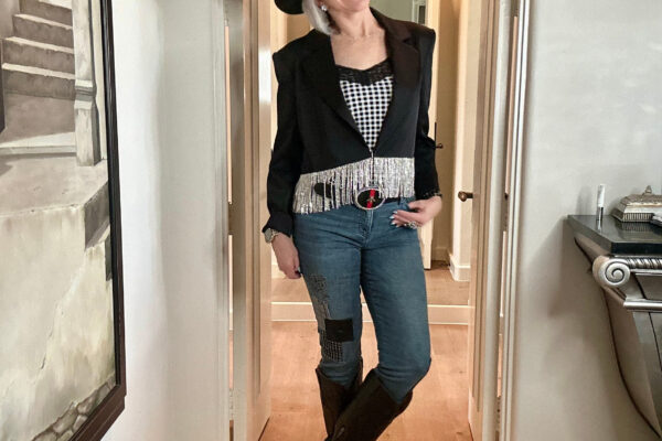 Sheree Frede of SheShe Show in black cropped blazer with rhinestone fringe, plaid cami, denim jeans, black knee high boots and black felt cowboy hat for western wear rodeo.