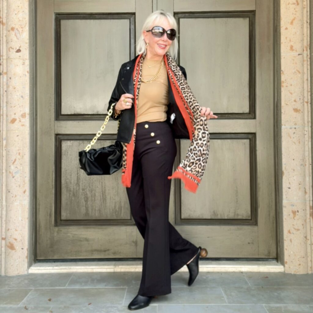 Neutral top paired with black pants with trending leopard scarf