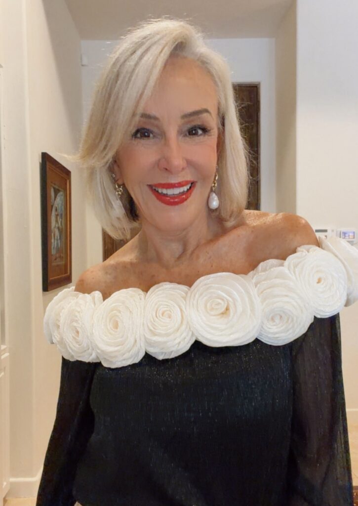 Sheree head shot wearing a black top with white flowers around shoulders